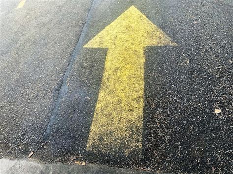 Premium Photo A Yellow Arrow Painted On The Asphalt