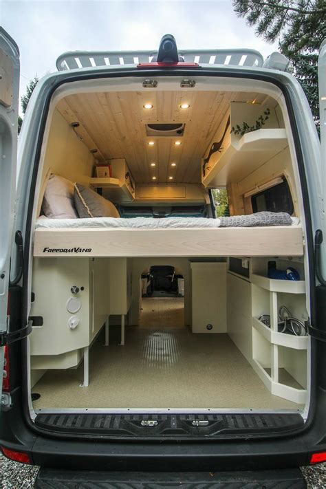 The Back End Of A White Van With Its Doors Open And Beds In Its Cargo Area