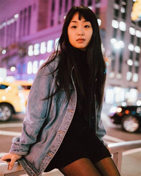 a woman sitting on a rail in the city at night