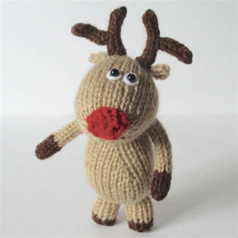 A Knitted Reindeer Doll With A Red Nose And Scarf On It S Chest