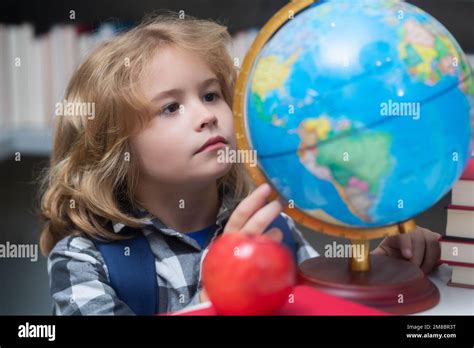 Niño de la escuela que mira el globo en la biblioteca en la escuela