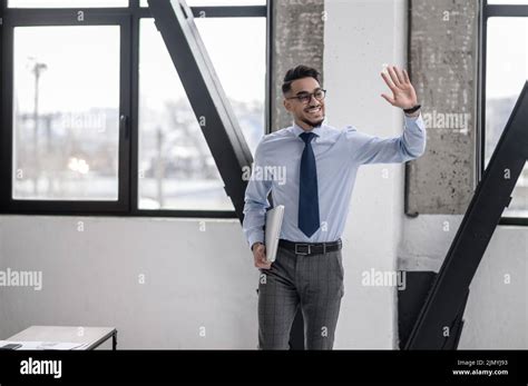 Man With Raised Hand Smiling To Side Stock Photo Alamy