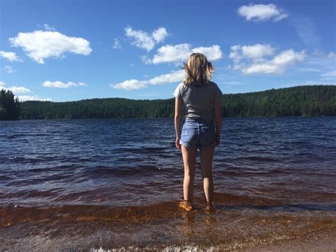 Premium Photo Rear View Of Woman Standing At Lakeshore Against Blue Sky