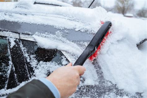 A Man Cleans His Car Covered In Snow After A Heavy Snowfall Stock Photo