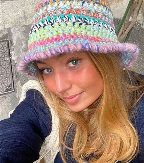 A Woman Wearing A Multicolored Hat And Posing For The Camera With Her