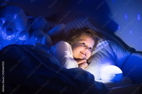 Little girl reading a book in bed Stock Photo | Adobe Stock