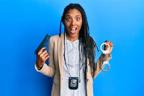 African American Police Woman Holding Gun And Handcuffs Celebrating