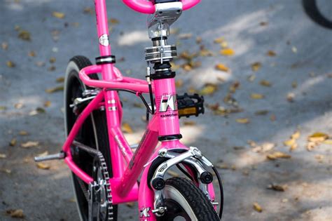 A Pink Bike Parked On The Side Of A Road Next To A Bicycle Rack And