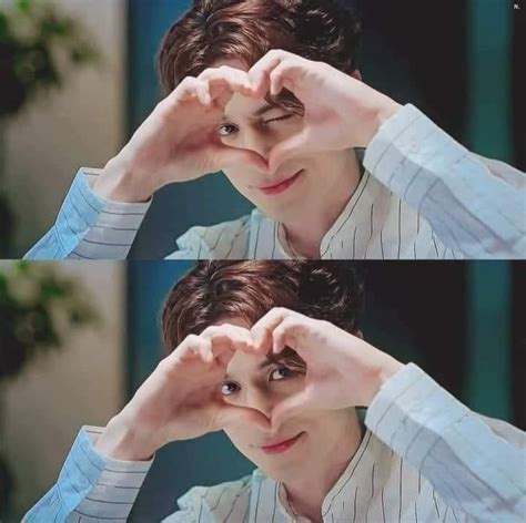 The Man Is Making A Heart Sign With His Hands While Wearing A Blue And