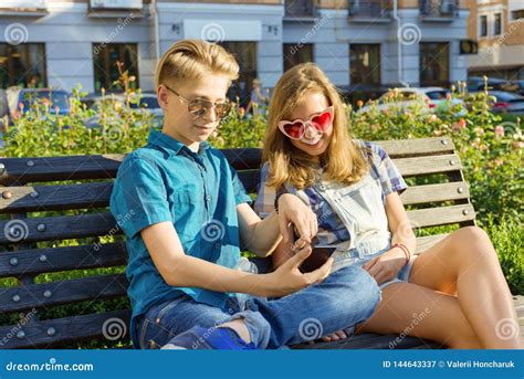 Amigos Adolescentes Menina E Menino Que Sentam Se No Banco Na Cidade