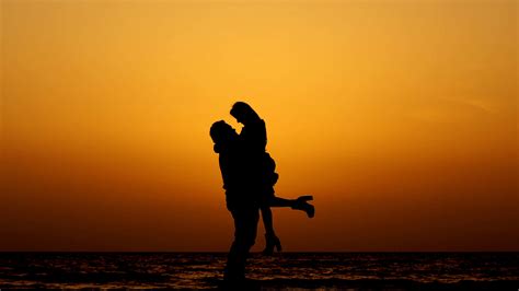 Download Caption: Sunset Embrace at the Seashore Wallpaper | Wallpapers.com