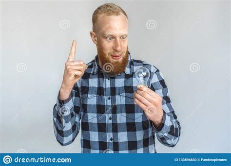 Freestyle Mature Man Standing Isolated On Grey Looking At Light Bulb