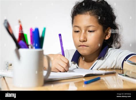 Close Up Of A Brunette Latina Girl Studying At Her Desk With A Bored Look On Her Face Stock