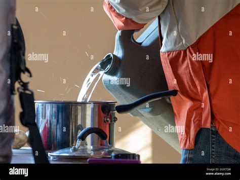 Man filling a metal cooking pot with water reserve in a container ...