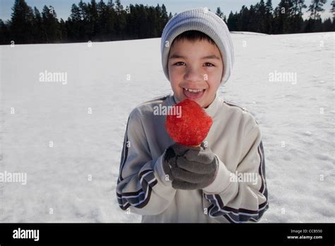 Niño De 10 A 12 Años De Edad Comiendo Un Cono De Nieve Afuera En Un Día De Invierno Fotografía