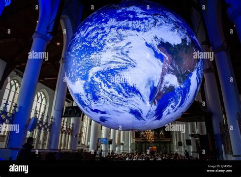 A Music Band Is Seen Playing Under A Big Earth Ball Gaia Is A Touring