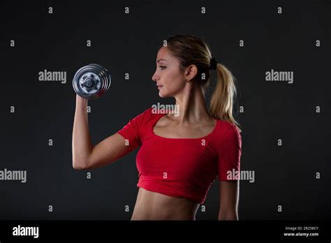 Fitness Passionate Blonde Lifting Weight Emphasizing Her Fit Stomach Red Gym Top Black Micro