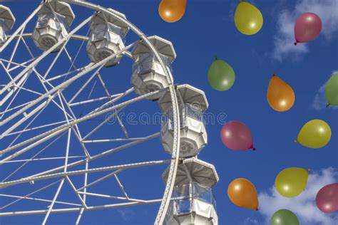 Ferris Wheel In An Amusement Park Against A Blue Sky With Balloons In