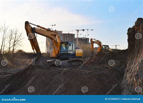 Excavator On Earthworks At Construction Site On Sunset Backround