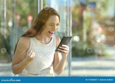 Excited Commuter Checking Phone Sitting In A Bus Stop Stock Image