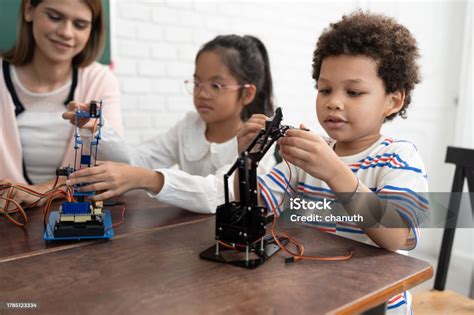 Happy African American Kid Boy Studying With Electric Robot And Friend