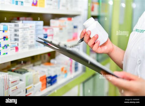 Pharmacist Holding Medicine Bottle And Prescription Chart For Filling