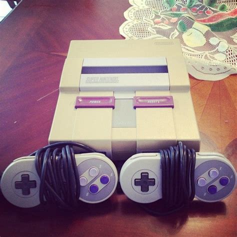 An Old Nintendo Game Console Sitting On Top Of A Wooden Table Next To