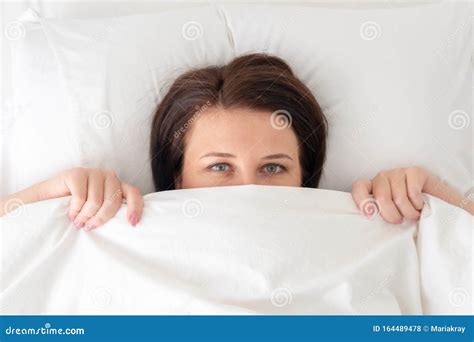 Portrait Of Young Beautiful Woman In Bed Looking From Under Blanket