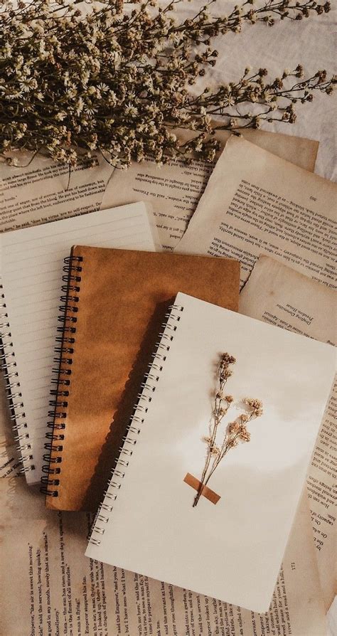 Three Notebooks With Flowers Sitting On Top Of An Open Book Next To