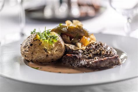 Well Done Rib Eye Steak Detail On A Plate With Baked Potato And Parsley