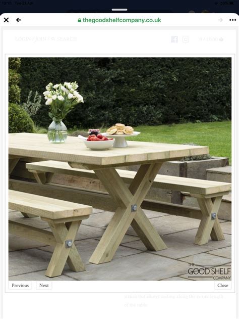 A Wooden Picnic Table With Two Benches In Front Of It And Flowers On