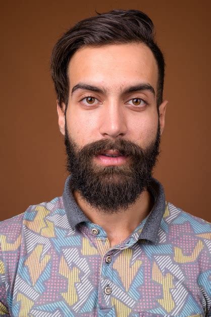 premium photo young handsome bearded persian man  brown wall
