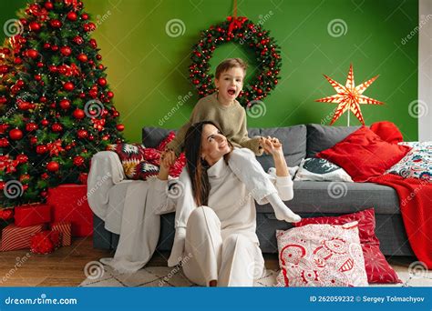 Mother Sitting On A Sofa With Her Son In Living Room Decorated For