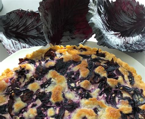 A Pie On A Plate With Lettuce And Other Food Items In The Background