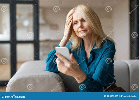 Upset Unhappy Mature Woman Using Cellphone And Touching Head Reading