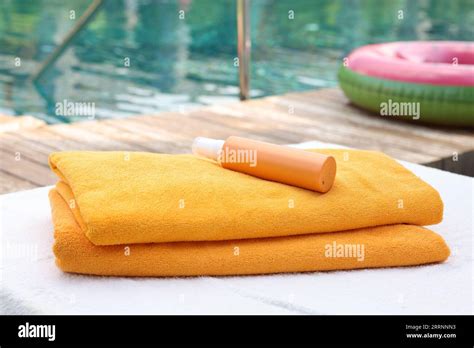 Beach Towels And Sunscreen On Sun Lounger Near Outdoor Swimming Pool