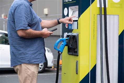 Man Holding Phone While Using EV Charger