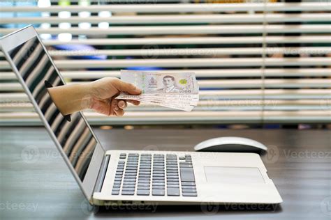 Hand Holding Thai 5000 Baht Banknotes Coming Out From Computer Screen