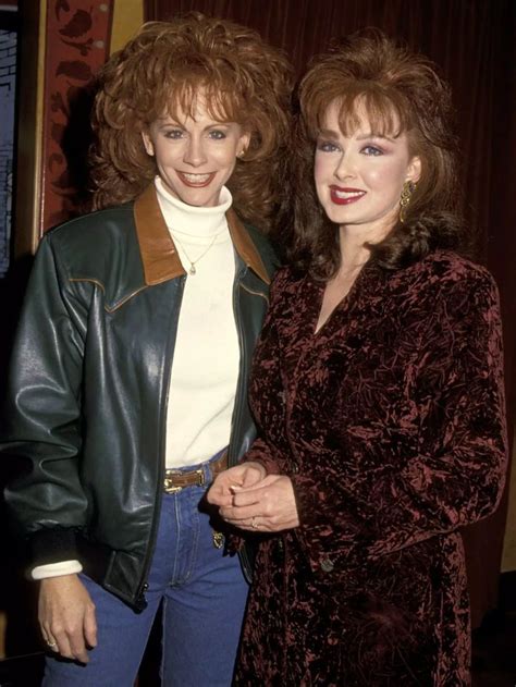 two women standing next to each other wearing jackets