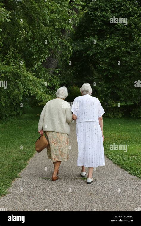 Two Elderly Women Walking Hand In Hand As Seen From Behind Stock Photo