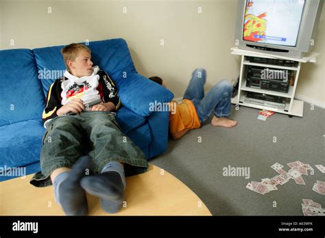 portrait of two young boys glued to the television, one with his feet ...