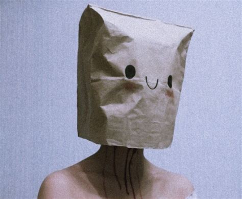 A Woman Wearing A Paper Bag Over Her Head With A Face Drawn On The Side