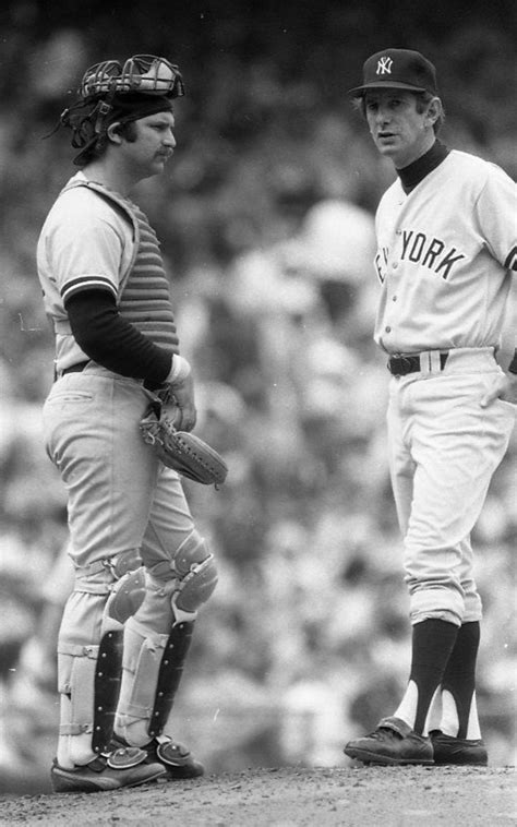 Two Baseball Players Standing Next To Each Other On A Field