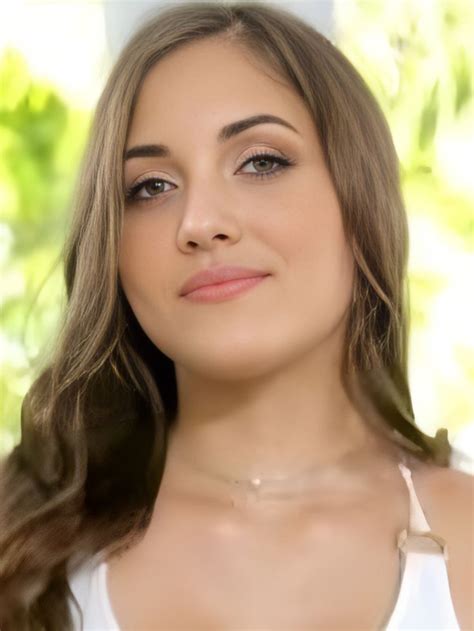 A Woman With Long Brown Hair Wearing A White Tank Top And Looking At