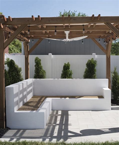 A White Bench Sitting Under A Wooden Pergol