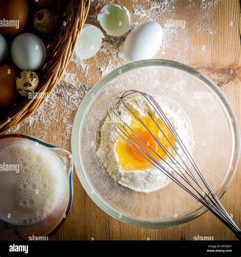 Overhead Shot Of Egg And Flour In Mixing Bowl With Basket Of Eggs And