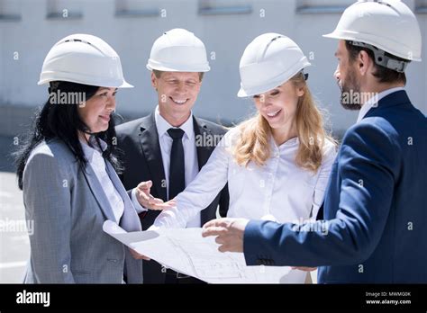 Professional Team Of Smiling Architects In Hard Hats Working Together