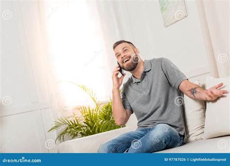 Cheerful Bearded Man Talking On Smartphone And Smiling While Sitting On