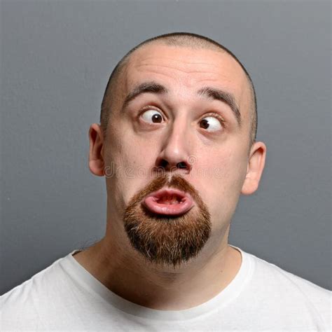 Portrait Of A Man Making Funny Face Against Gray Background Stock Photo