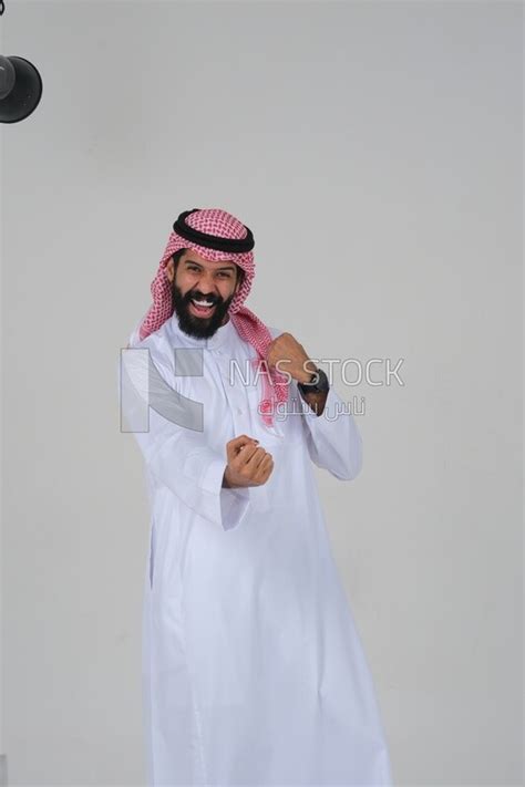 Saudi man wearing a white dress looks happy, facial gestures indicating ...